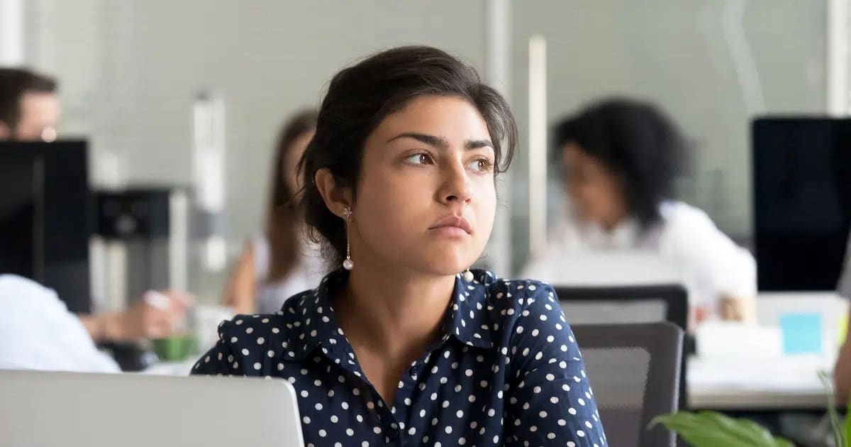 Indian business woman in deep thought looking away from laptop